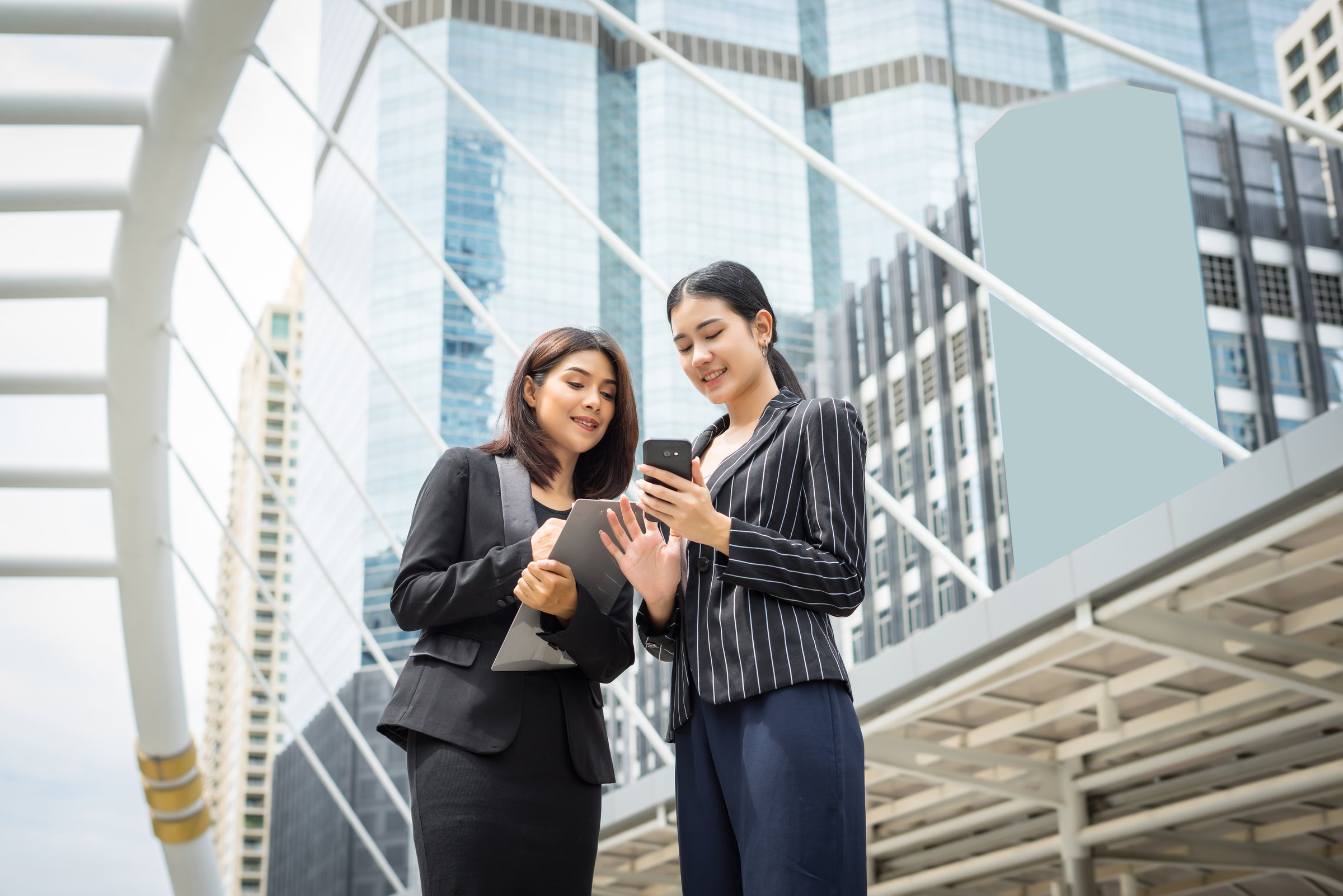Two businesswomen using a mobile phone for cashless payments